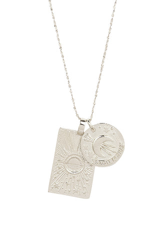 close-up-front-view-of-spell-s-sagittarius-stargazer-zodiac-necklace-charms-one-charm-is-of-a-rectangular-shape-and-features-a-sun-with-stars-while-the-other-charm-is-circular-and-features-the-zodiac-label-and-icon